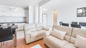 A modern living room with a sofa, a dining table, and a kitchen in the background. - Apartments Adriatic (Split)