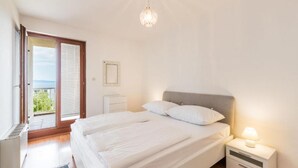 A bedroom with a bed, bedside table, and a view of the outdoors. - Apartments Adriatic (Split)