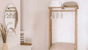 Ein schlicht eingerichteter Raum mit Etagenbett, einem runden Teppich, einem weißen Tisch mit Stühlen und einem Spiegel an der Wand.
