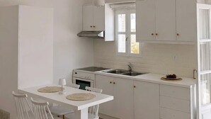 Eine moderne Küche mit weißen Schränken, einem Esstisch mit Stühlen und einem eingebauten Backofen.