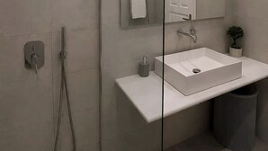 Ein modernes Badezimmer mit Duschkabine aus Glas, einem weißen Waschbecken und einem Spiegel.