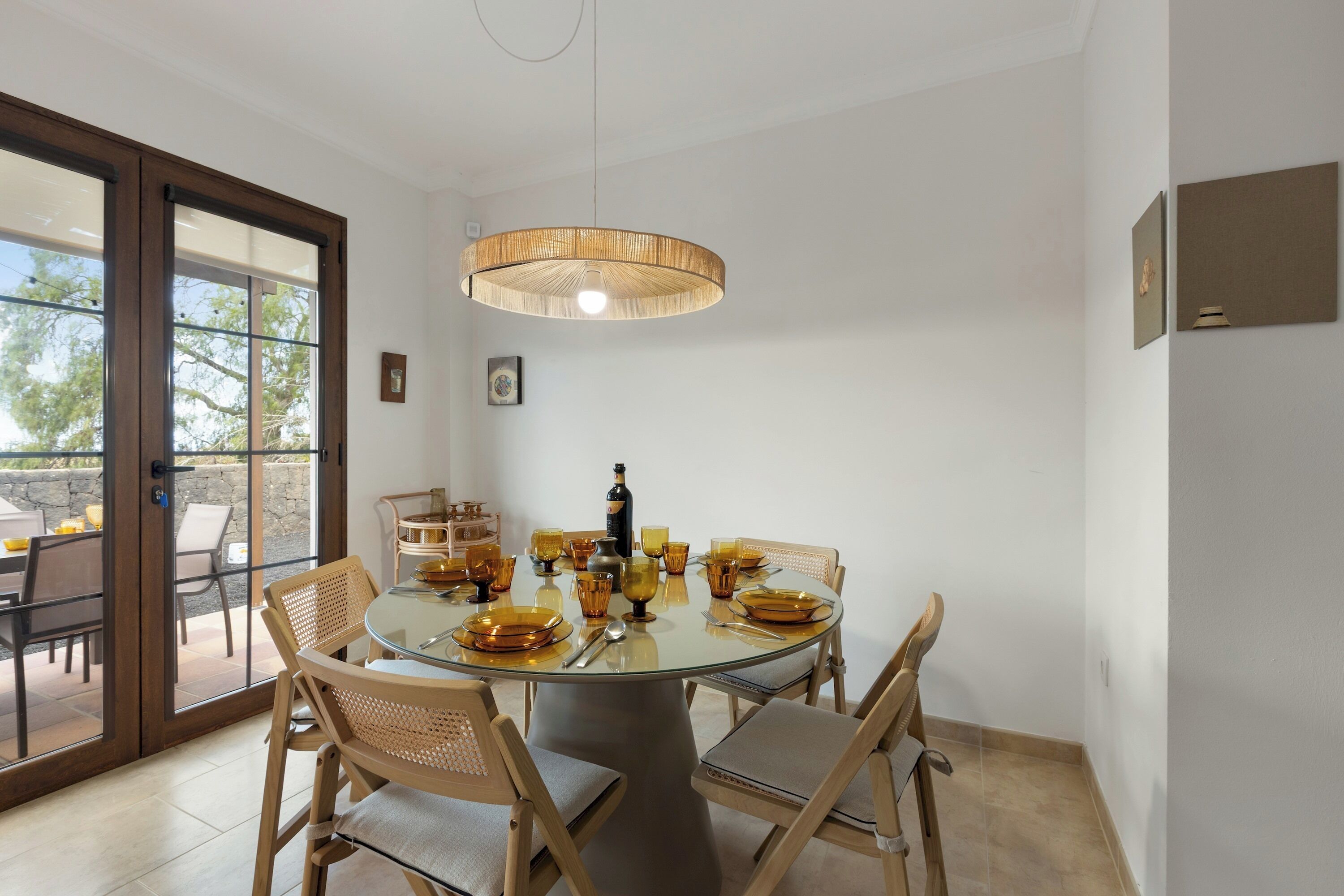 A dining area with a round table, chairs, and a hanging light fixture.