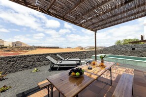 Una terraza con una mesa, sillas y vistas a un paisaje volcánico.