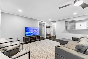 A modern living room with a flat-screen TV, a sofa, a coffee table, and a ceiling fan. - Mimosa Light cosy house  Close to DFW & AT&T & six flags (Richland Hills)