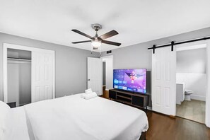 A hotel room with a bed, a ceiling fan, a TV, and a bathroom visible through an open door. - Mimosa Light cosy house  Close to DFW & AT&T & six flags (Richland Hills)