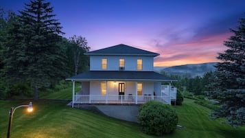 Une maison à deux étages avec un porche, une petite terrasse et une pelouse bien entretenue.