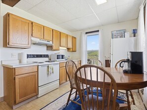 A kitchen with wooden cabinets, a stove, a microwave, and a dining table with chairs.
