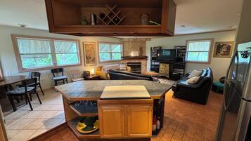 A spacious kitchen with a central island, dining area with chairs, and a living room with a sofa.