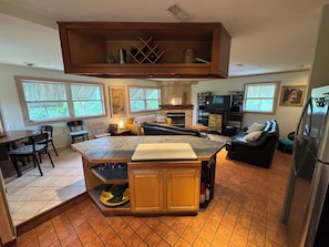 A spacious kitchen with a central island, dining area with chairs, and a living room with a sofa. - Cozy, 3-Bedroom Bungalow just a short walk to beach and sound. (Rodanthe)