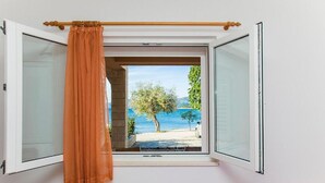Una camera da letto con finestra aperta, un letto e vista sulla spiaggia.