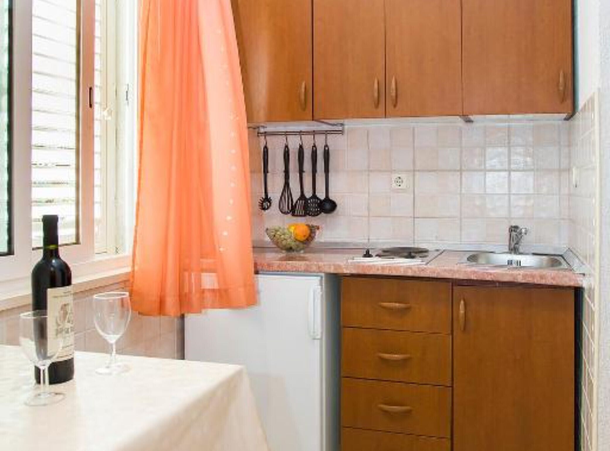Una cucina con mobili in legno, un piano di lavoro, un lavello e una finestra con persiane.