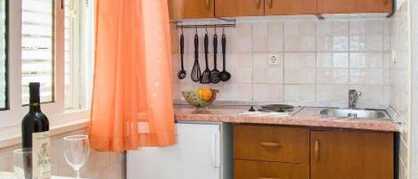 Una cucina con mobili in legno, un piano di lavoro, un lavello e una finestra con persiane.
