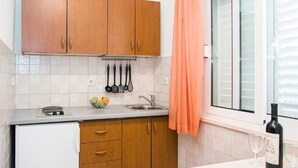 Eine Küche mit Holzausstattung, einer Arbeitsplatte, einem Spülbecken und einem Fenster mit Jalousien.