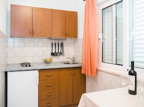 Eine Küche mit Holzausstattung, einer Arbeitsplatte, einem Spülbecken und einem Fenster mit Jalousien.