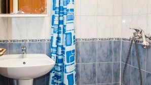 Ein Badezimmer mit Waschbecken, Spiegel, Dusche und einem blauen Duschvorhang mit Muster.