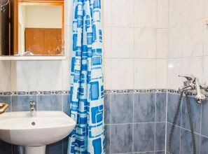 Ein Badezimmer mit Waschbecken, Spiegel, Dusche und einem blauen Duschvorhang mit Muster.