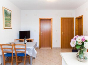 Ein Essbereich mit Tisch, Stühlen, einem Fernseher und einer Tür.