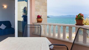 A balcony with a table, chairs, and potted plants, overlooking a body of water and distant land. - one bedroom with balcony and sea view A4 (Janjina)