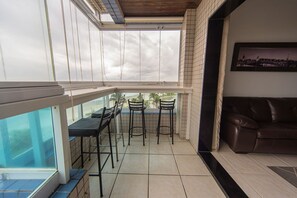 Uma varanda com vista, um sofá e uma mesa com cadeiras.