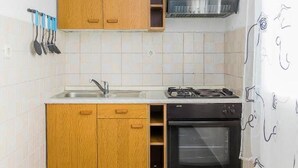 Une cuisine dotée de meubles en bois, d’une hotte en acier inoxydable, d’une cuisinière à gaz, d’un évier et d’un lave-vaisselle.