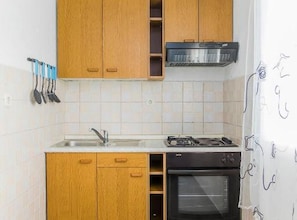 A kitchen with wooden cabinets, a stainless steel range hood, a gas stove, a sink, and a dishwasher. - one bedroom with balconies and sea view A5 (Janjina)