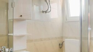 Une salle de bain équipée d’un lavabo, d’un miroir, d’une douche et de toilettes.