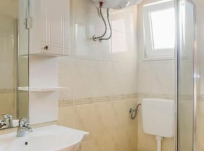 A bathroom with a sink, mirror, shower, and toilet. - one bedroom with balconies and sea view A5 (Janjina)