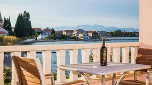 Un balcon avec une table, des chaises et une bouteille de vin.