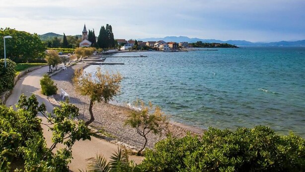 Une vue sur la côte, avec une promenade dallée, une église et des immeubles d’habitation.