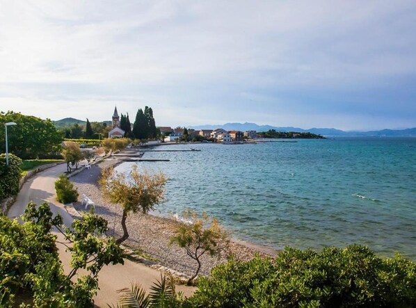 A coastal view with a paved walkway, a church, and residential buildings. - one bedroom with balconies and sea view A5 (Janjina)