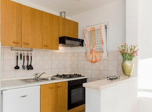 A kitchen with wooden cabinets, a gas stove, a sink, and a window with a curtain. - two bedroom with balcony and sea view A6 (Janjina)