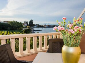 A balcony with a view of a river, a vase with flowers, and a table with chairs. - two bedroom with balcony and sea view A6 (Janjina)