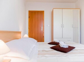 A hotel room with a bed, a wooden door, and a wardrobe. - two bedroom with balcony and sea view A6 (Janjina)