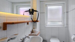 Une salle de bain équipée d’un lavabo, de toilettes et d’une fenêtre en verre dépoli.