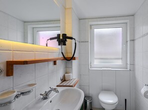 A bathroom with a sink, toilet, and a window with frosted glass. - Classic Studio Apartment (Komiza)