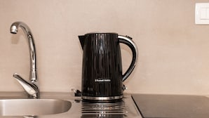 Ett kök med en modern blandare, en svart kaffebryggare från Russell Hobbs och en beige bänkskiva.