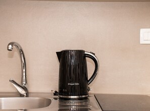 A kitchen with a modern faucet, a black Russell Hobbs coffee maker, and a beige countertop. - One Bedroom Apartment with Balcony (Komiza)