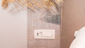 Ett vägguttag med en strömbrytare, en panel med strukturerad textil och ett runt, svart bord.