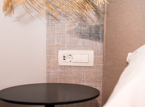 A wall-mounted power outlet with a switch, a textured fabric panel, and a round black table. - One Bedroom Apartment with Balcony (Komiza)