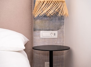 A room with a bed, a round black table, and a wall socket. - One Bedroom Apartment with Balcony (Komiza)