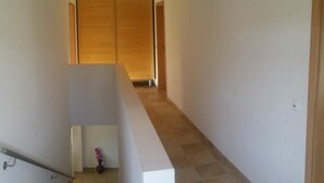 Una stretta scala conduce a una stanza con una porta in legno e un piccolo vaso con fiori.