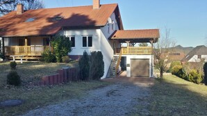 Una casa a due piani con un portico coperto, un garage e un vialetto in ghiaia.