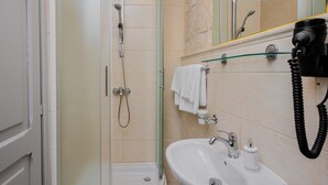 A bathroom with a glass shower enclosure, a sink with a mirror, and a hairdryer mounted on the wall. - Studio Apartment with Balcony (Komiza)