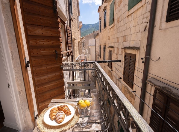 A balcony with a table set for breakfast, including croissants and a vase. - Studio Apartment with Balcony (Komiza)