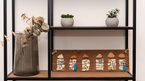 A shelf with decorative items including a vase with dried flowers, two potted plants, and a wooden display of stones. - Studio Apartment with Balcony (Komiza)