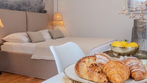 Un dormitorio con cama, una mesita de noche con croissants y un cuenco de limones.