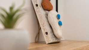 Decoración rústica de madera con textura irregular, una piedra marrón y dos botones azules.