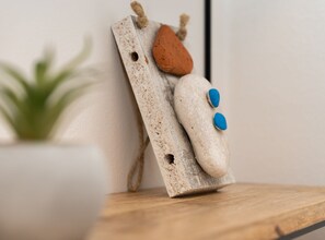 A rustic wooden wall decoration with a rough texture, a brown stone, and two blue buttons. - Comfort Studio Apartment (Komiza)
