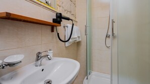 Un baño con lavamanos, espejo, toallero y ducha.