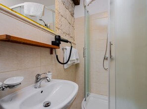 A bathroom with a sink, mirror, towel rack, and shower. - Comfort Studio Apartment (Komiza)